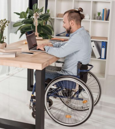 disabled man on wheelchair using laptop at office