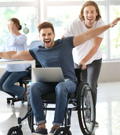 Handicapped young man with colleague having fun in office